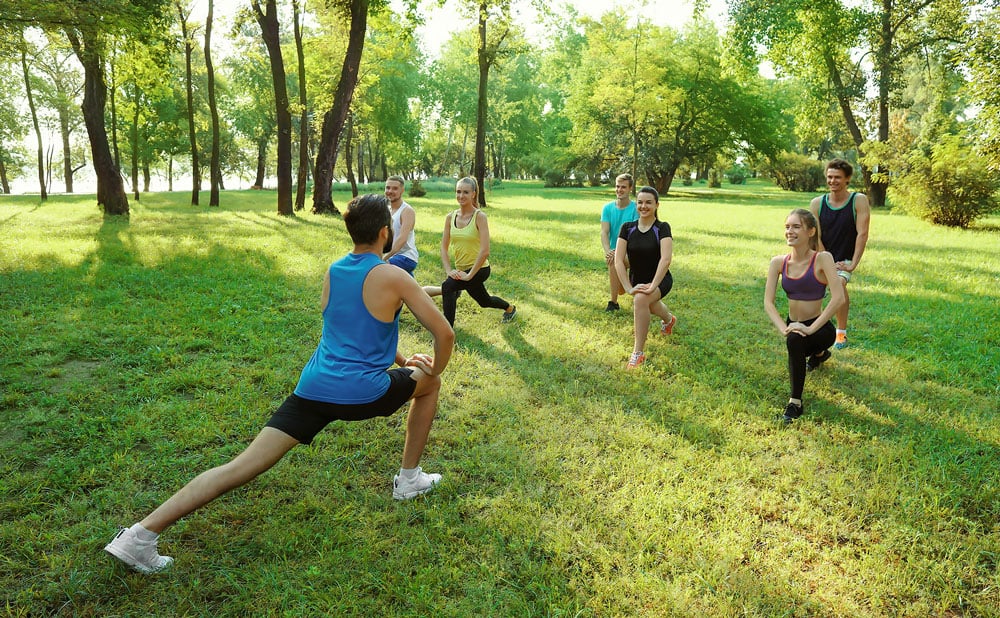 A group of colleagues doing a fitness class in the park.