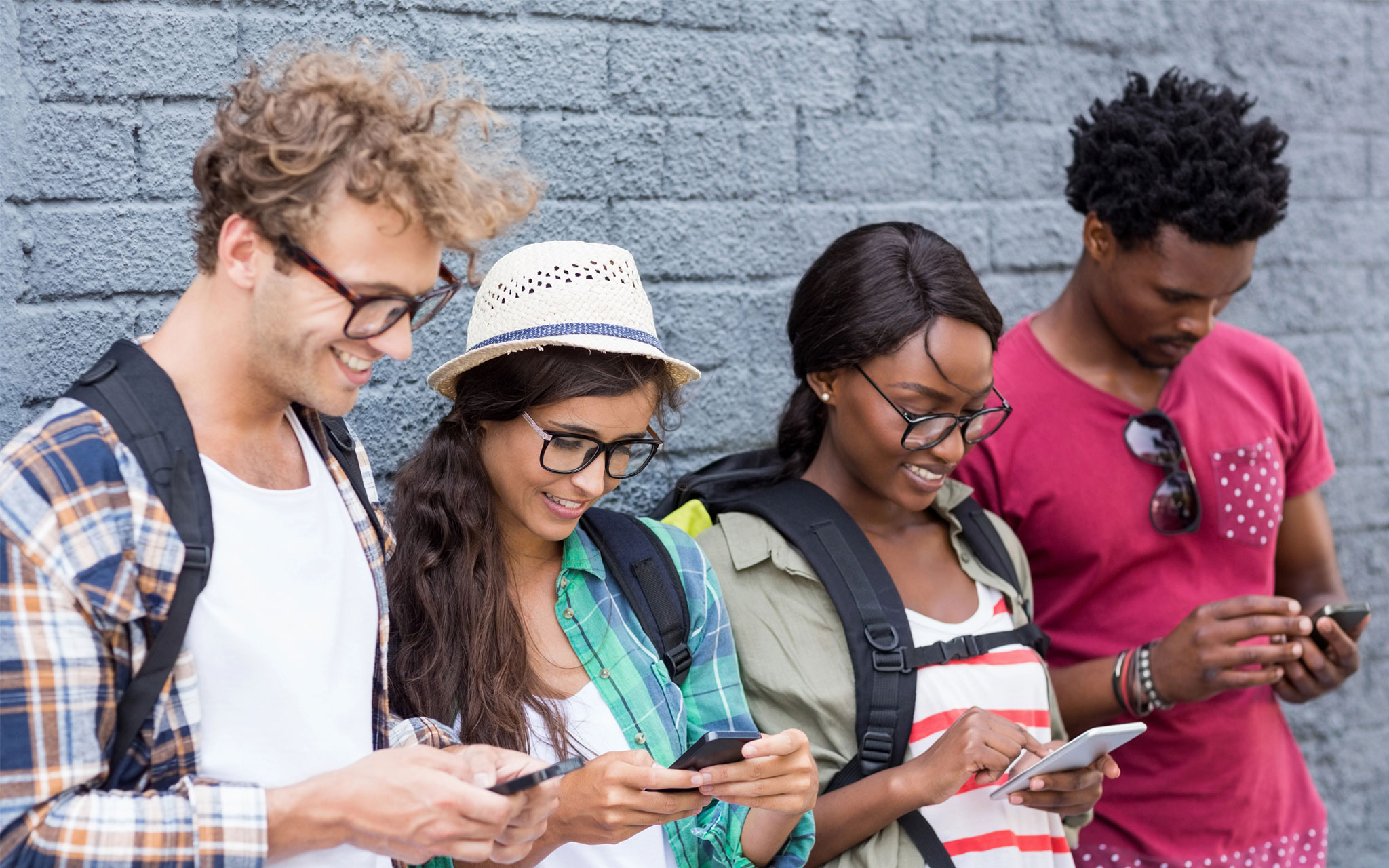 Friends on their phones leaning against a wall