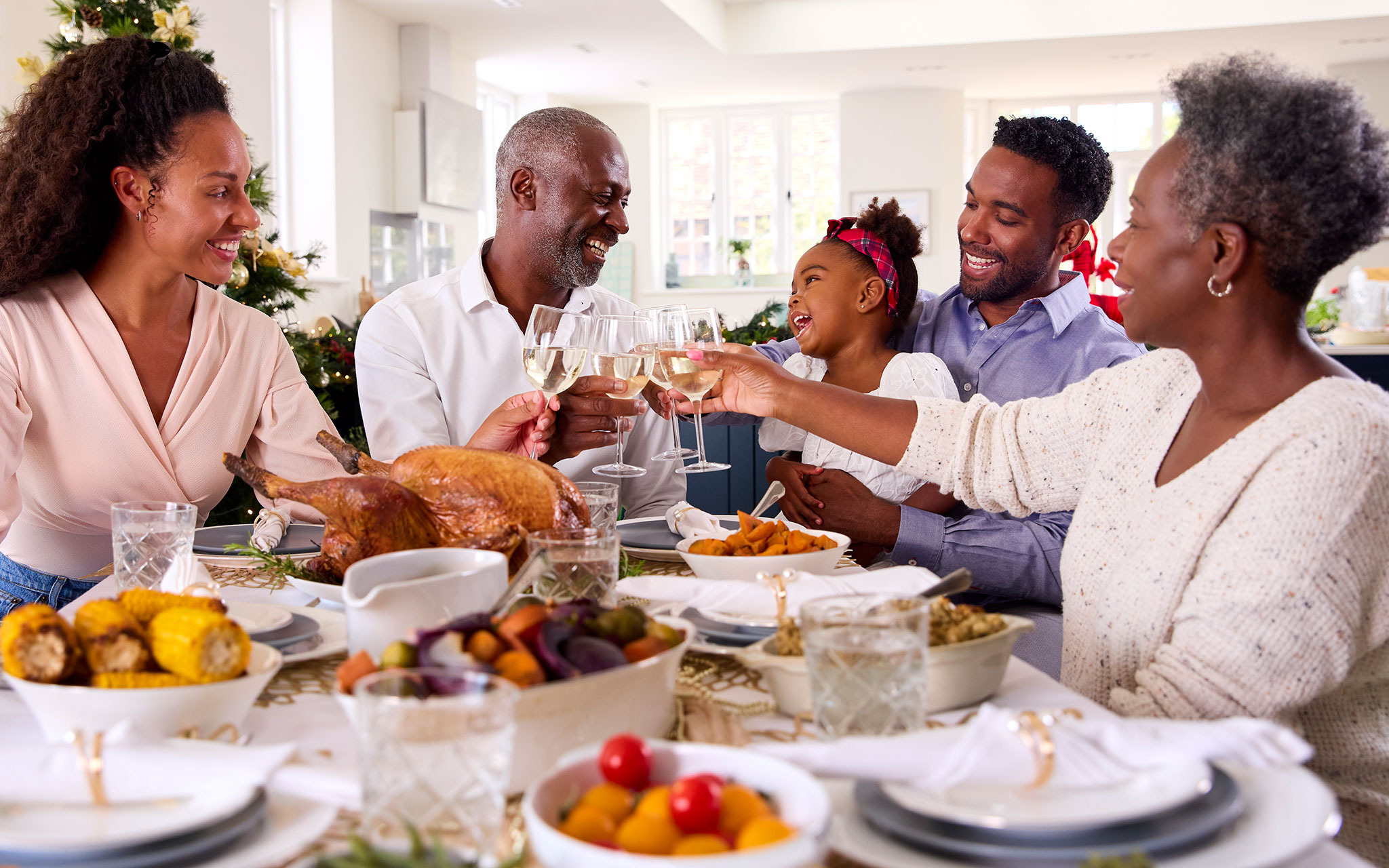 Multi-Generation Family Celebrating Christmas At Home Eating Meal And Making a Toast With Wine